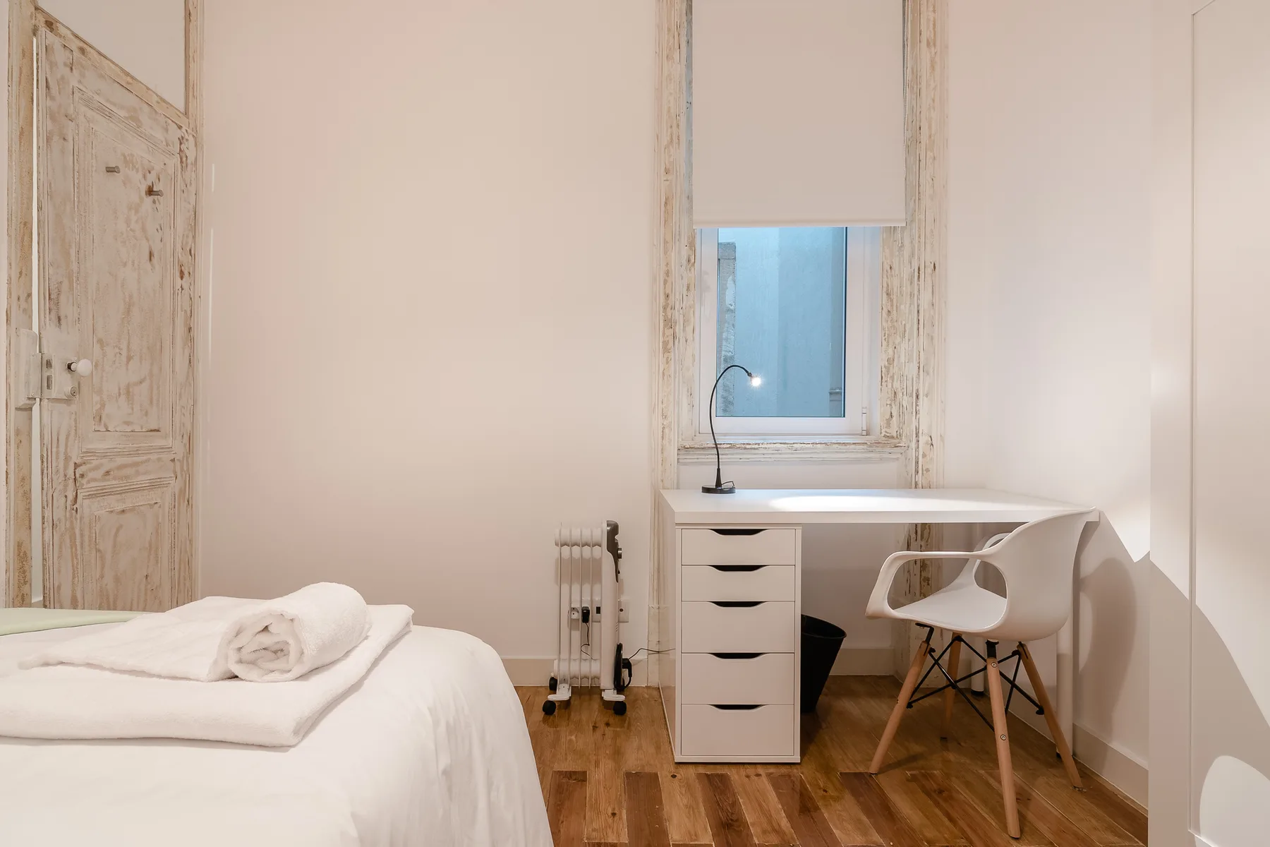 A bedroom with a bed and a desk beneath the window.