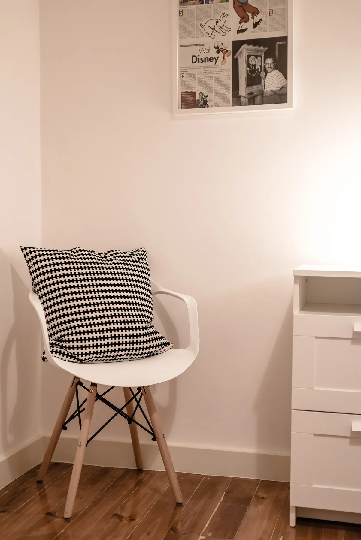 A white chair with a patterned cushion sits beside a drawer cabinet.