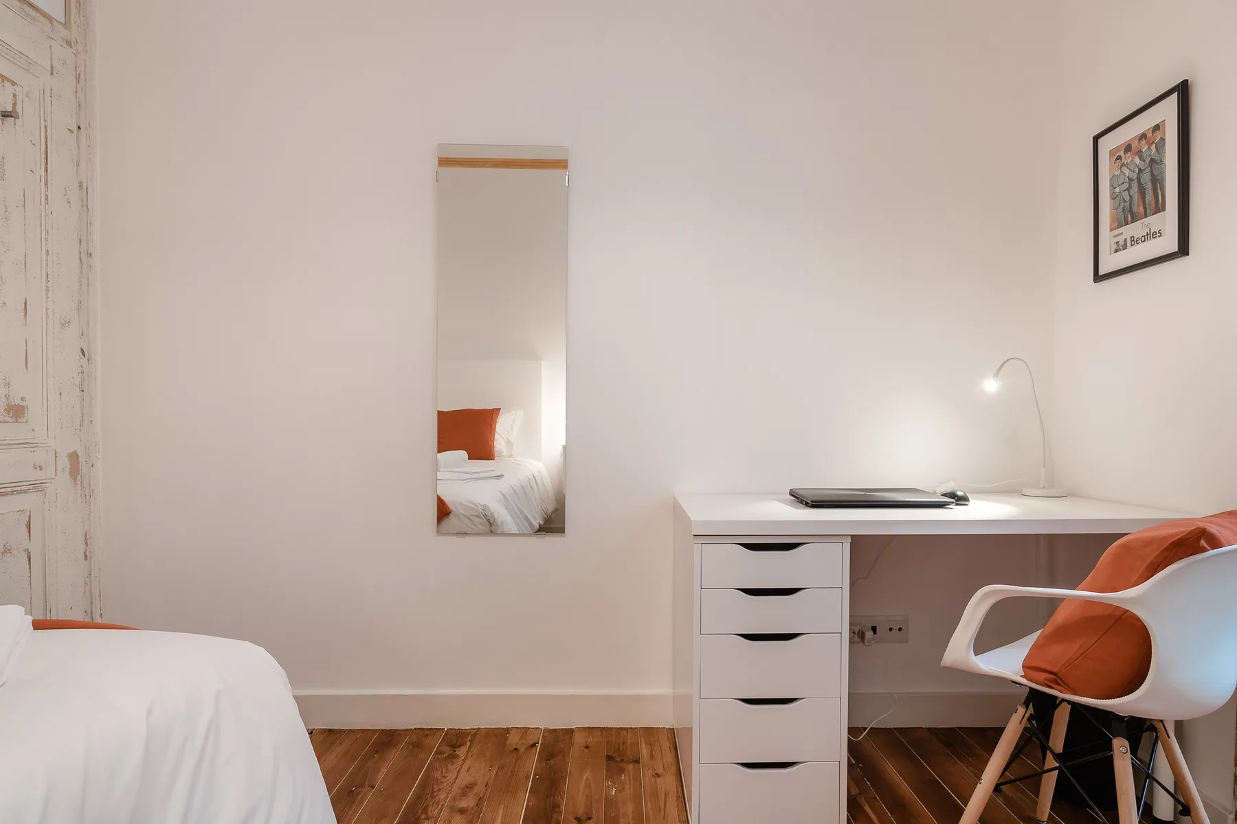 A bedroom with a desk and seating beside the bed.