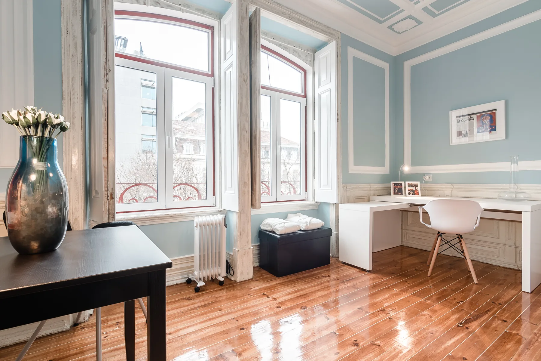 A bright room with tall windows, a desk, and polished wood flooring.