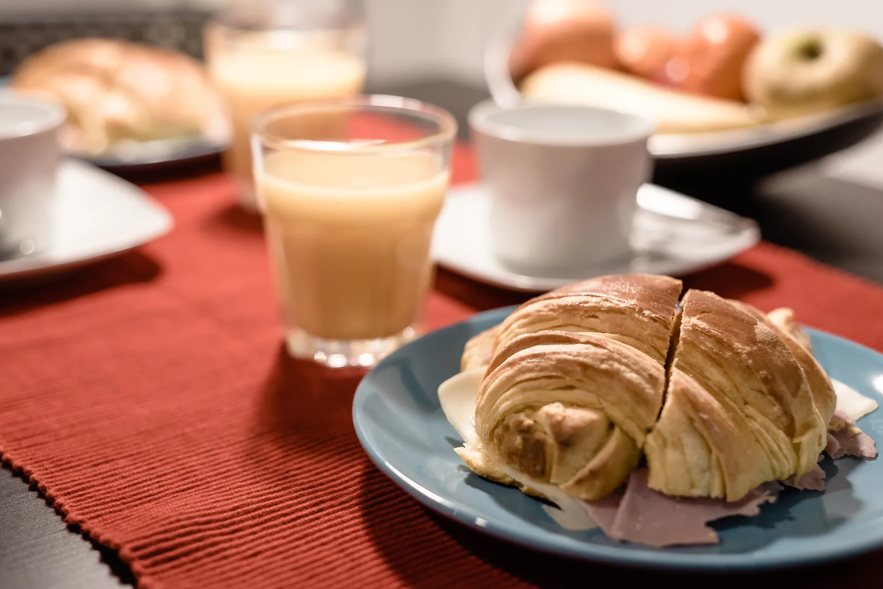 A breakfast table with pastries, cups, and a glass of juice.