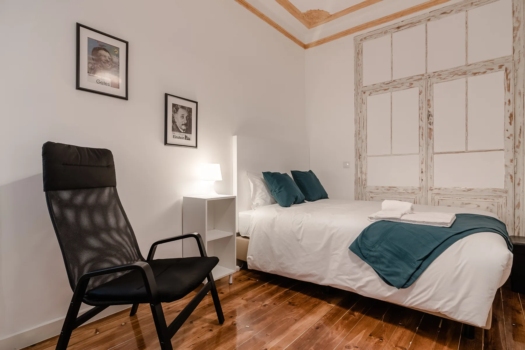 A bedroom with a bed dressed in white and teal linens.