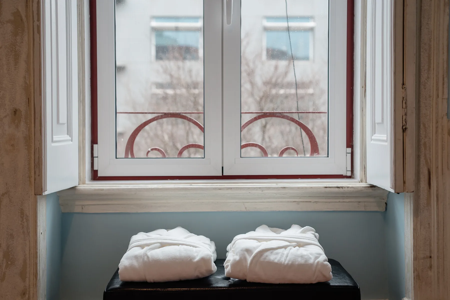 A window above a dark bench holds two folded white towels.
