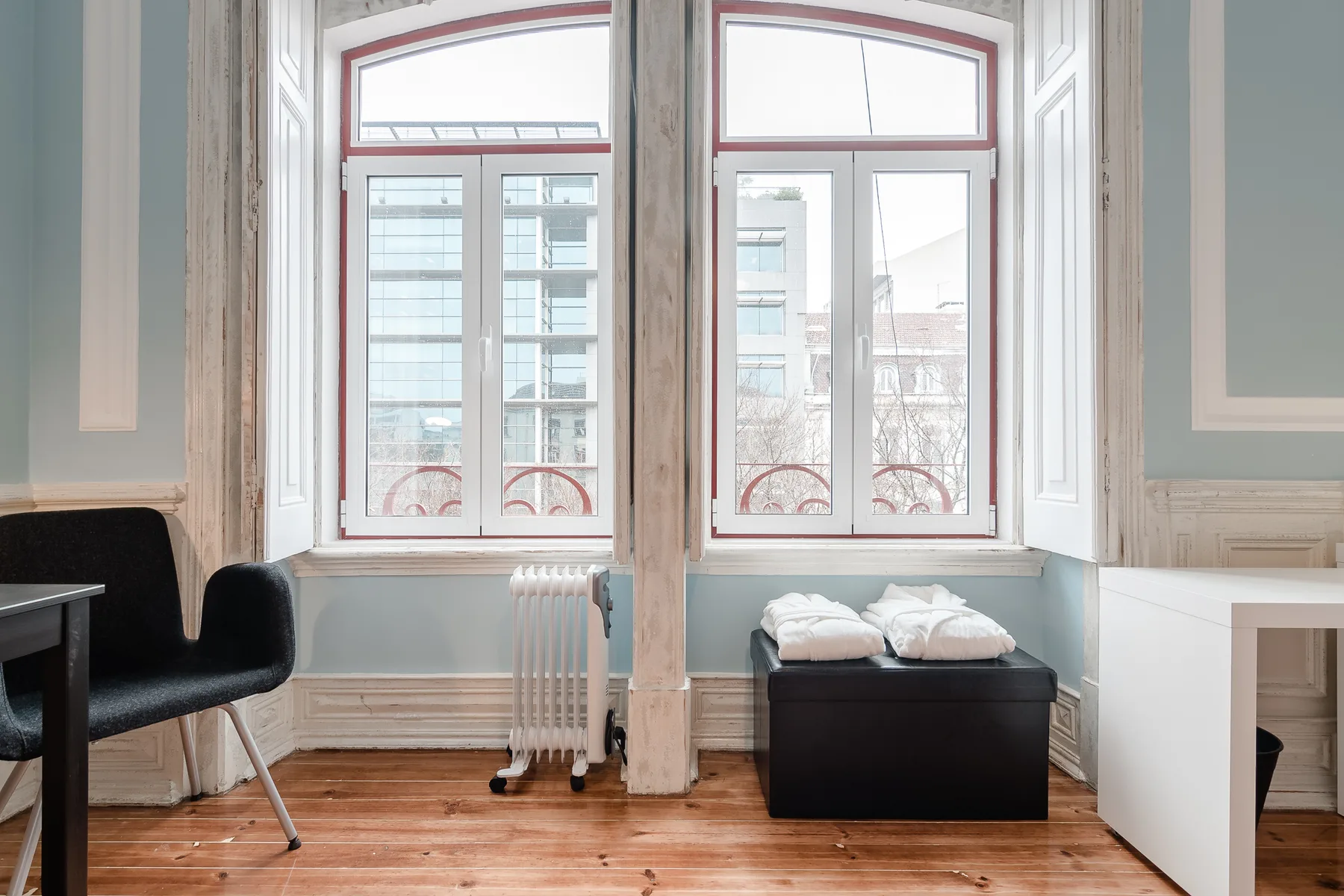 A bright room with tall windows, a radiator, and a bench.