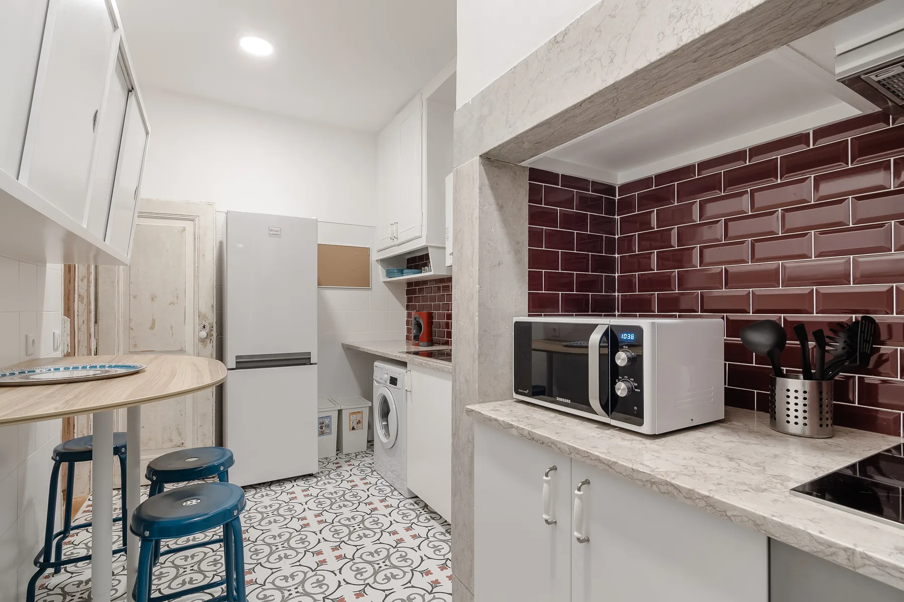 A compact kitchen with a refrigerator, washing machine, and countertop appliances.