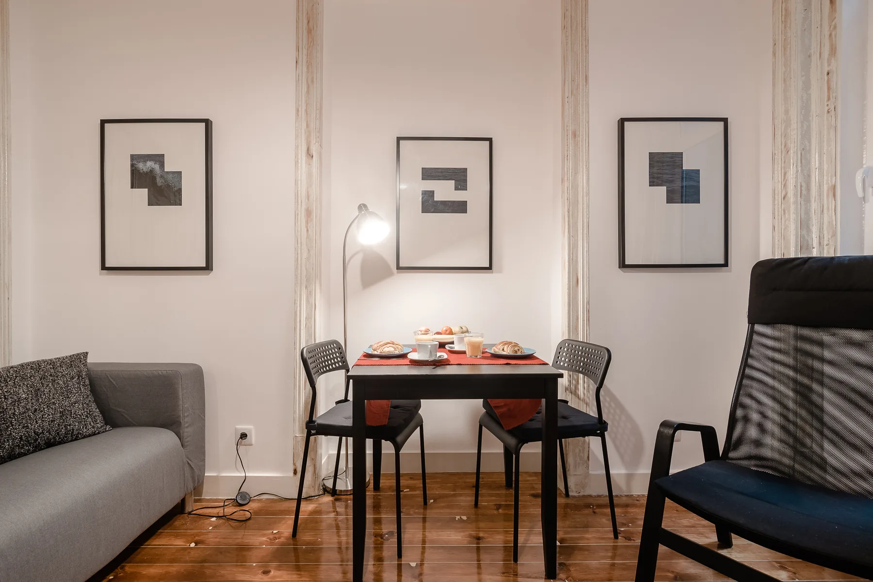 Una mesa de comedor y sillas están entre dos zonas de asiento, con cuadros en la pared.