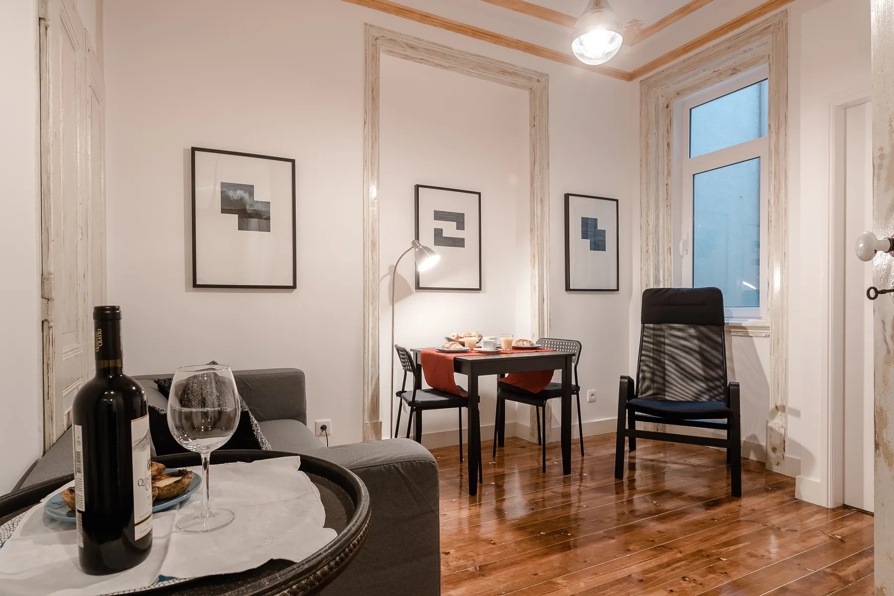 Una sala de estar y comedor con asientos, una mesa y cuadros enmarcados.