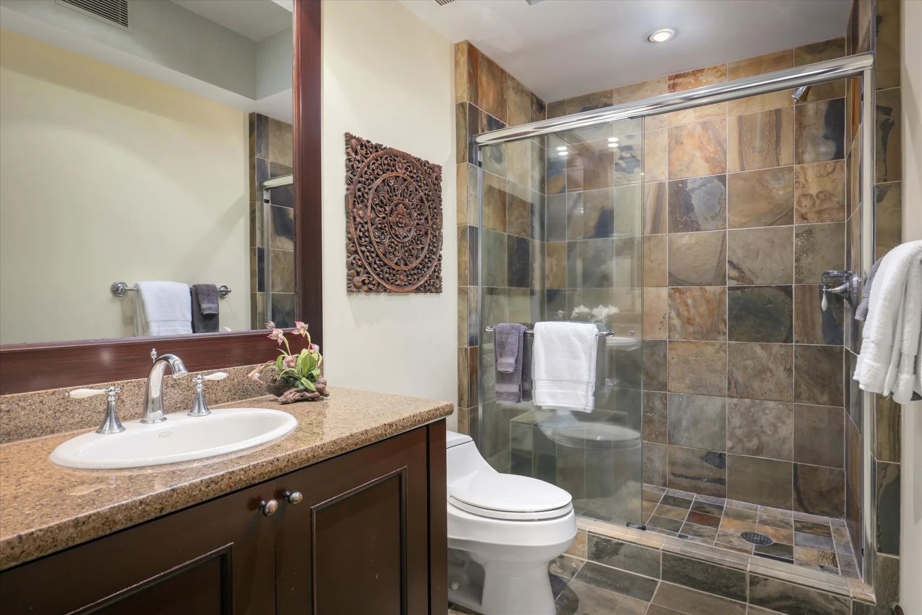 A bathroom with a sink vanity and a glass-enclosed shower.