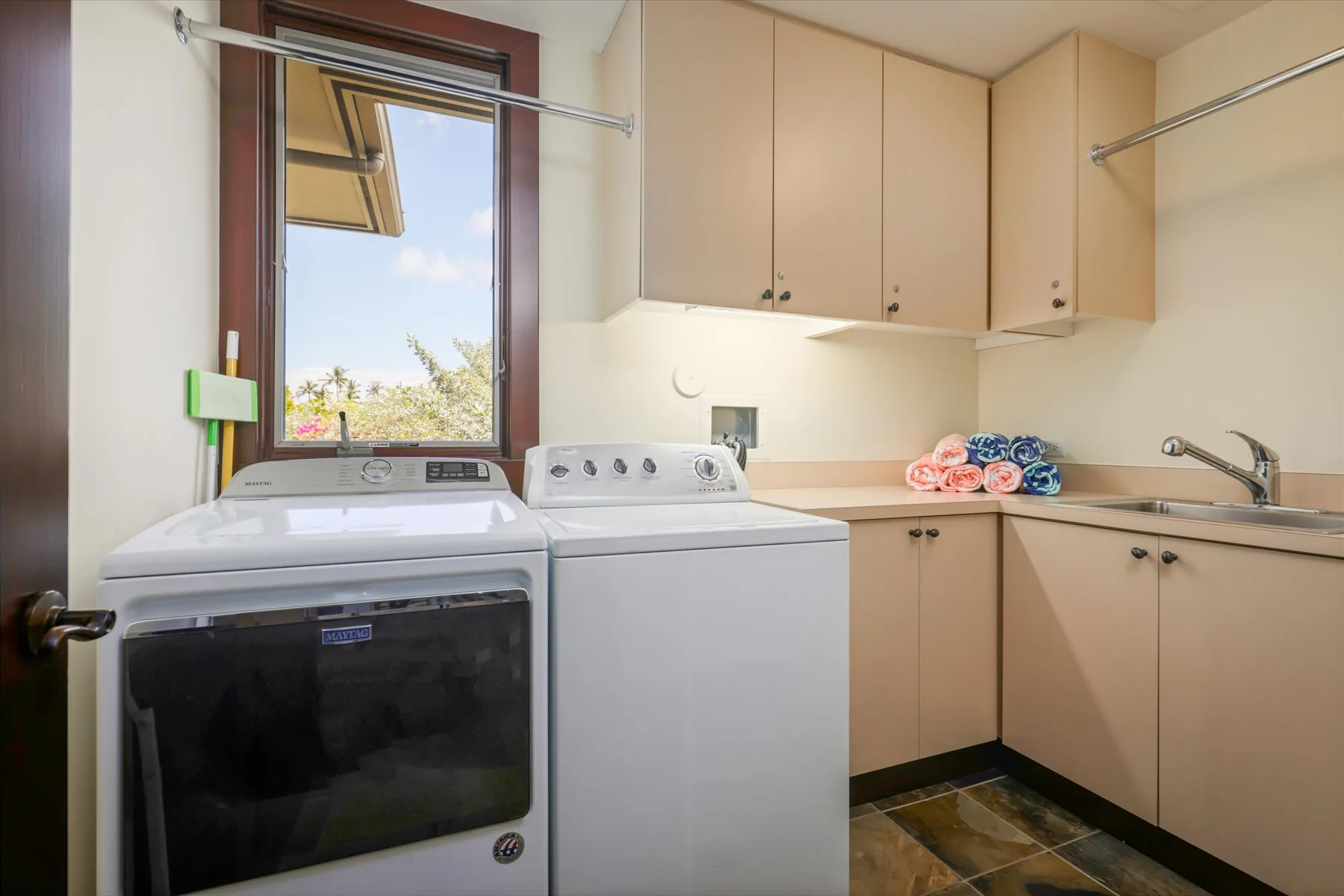 A laundry room with a washer, dryer, and beige cabinets.