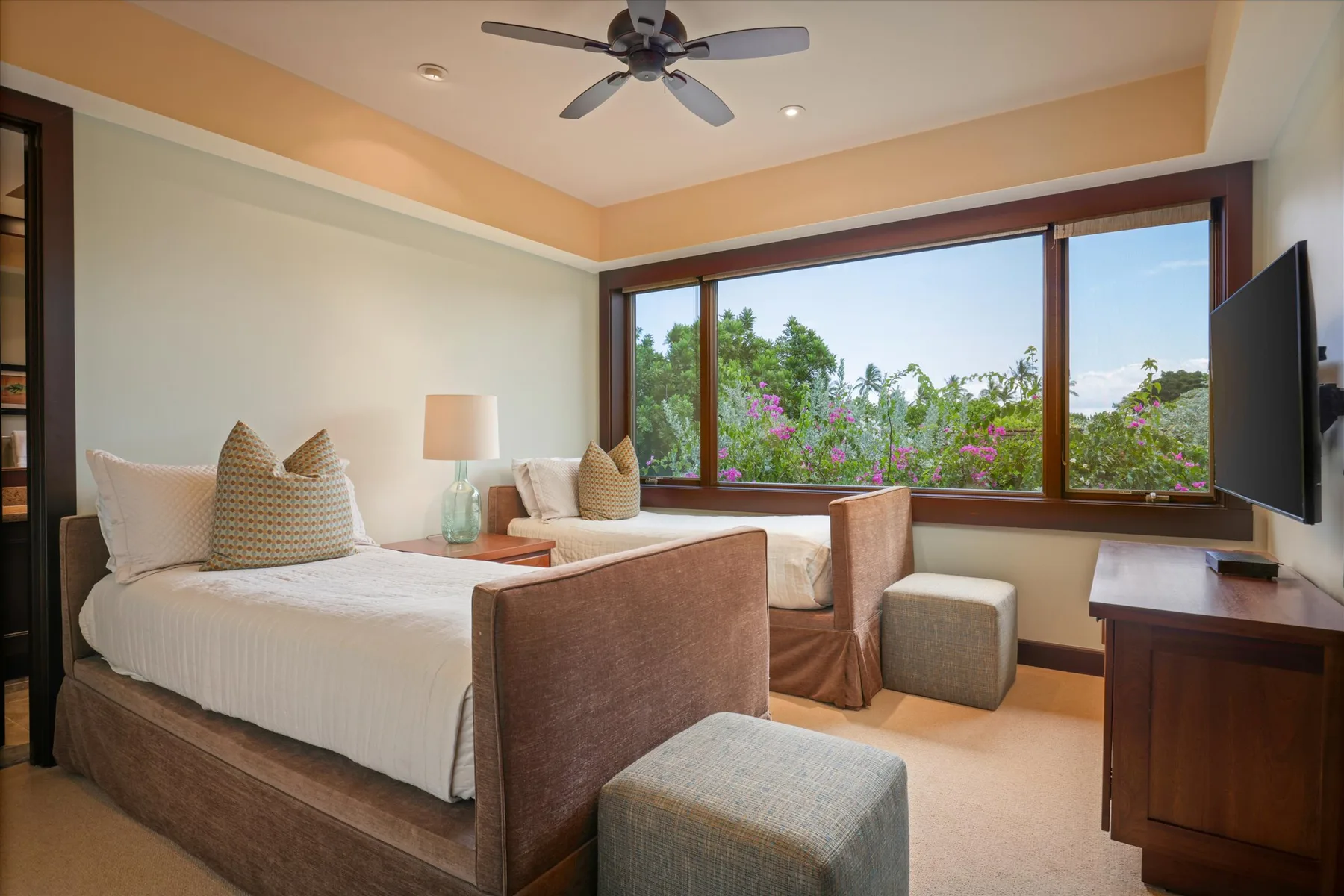 A bedroom with a bed, seating, and wide windows overlooking greenery.