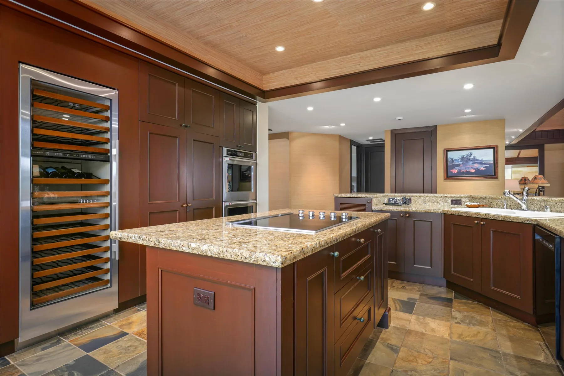 A spacious kitchen with dark cabinetry, a central island, and a wine cooler.