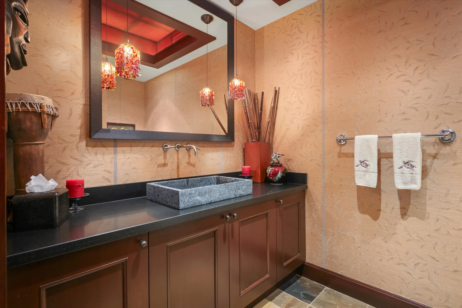 A bathroom vanity with a rectangular sink, large mirror, and towels on the wall.