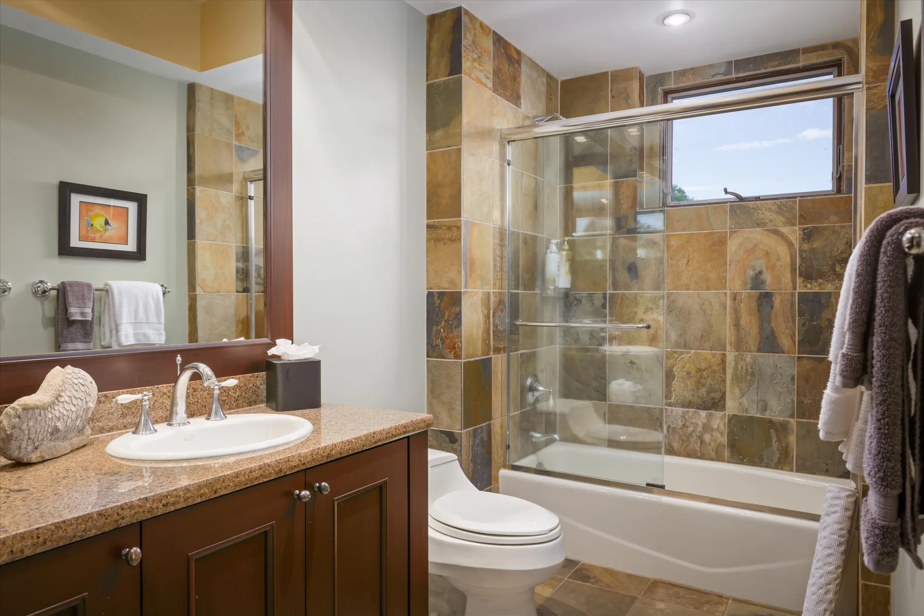 A bathroom with a sink, toilet, and glass-enclosed tub and shower.