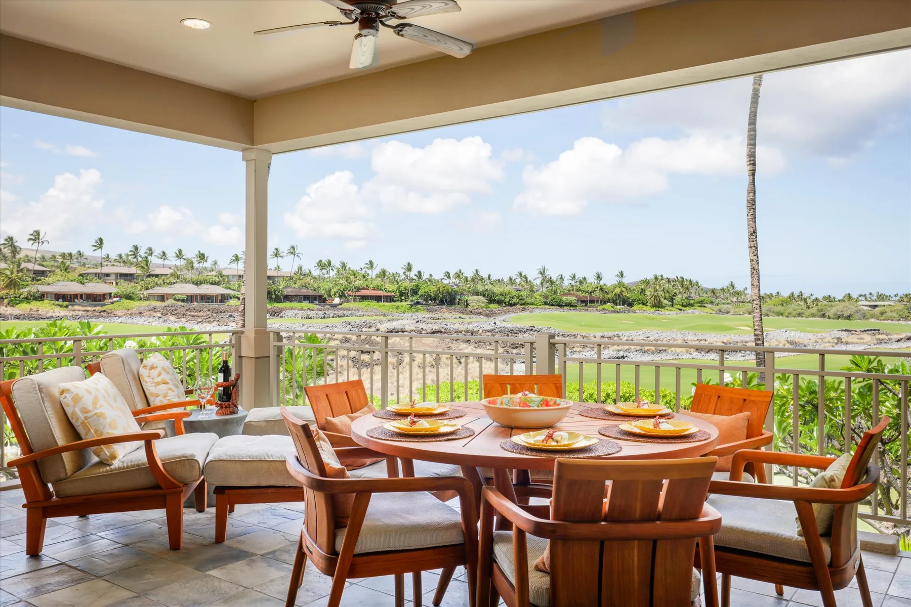 A covered outdoor dining area overlooks a green landscape and water.