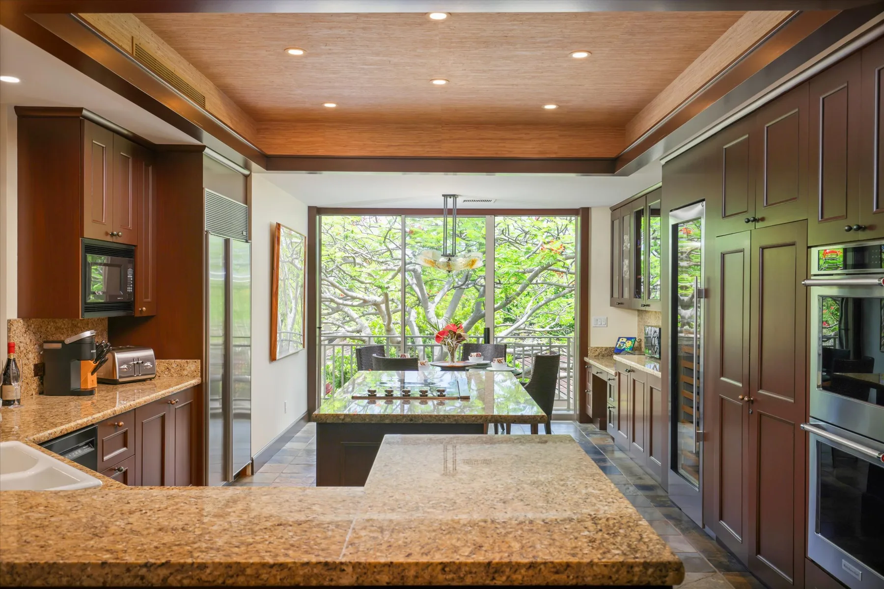 A spacious kitchen with a central island and a dining table by large windows.