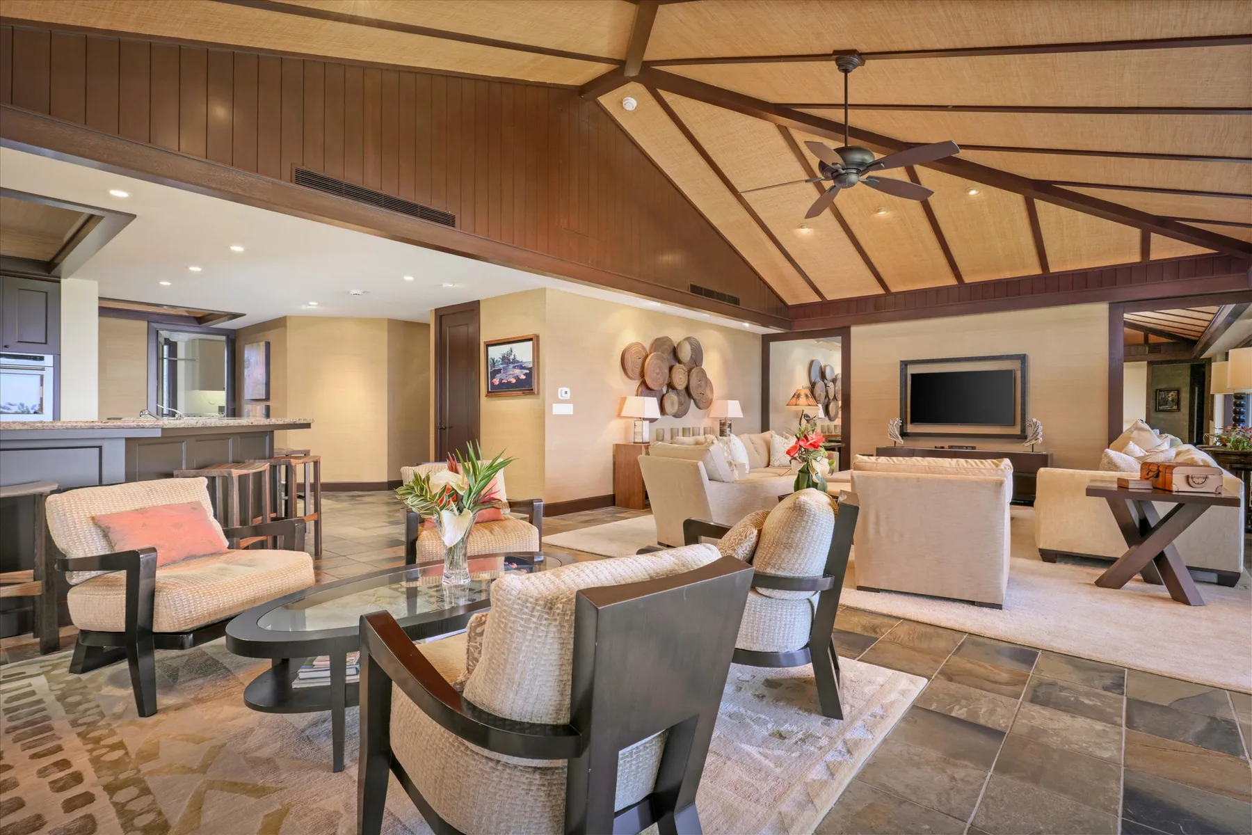 A spacious living room with seating around a coffee table beneath a wood-paneled ceiling.