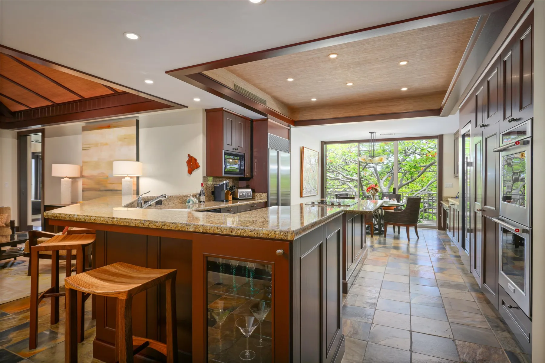 A spacious kitchen with a long island and dining area beside large windows.