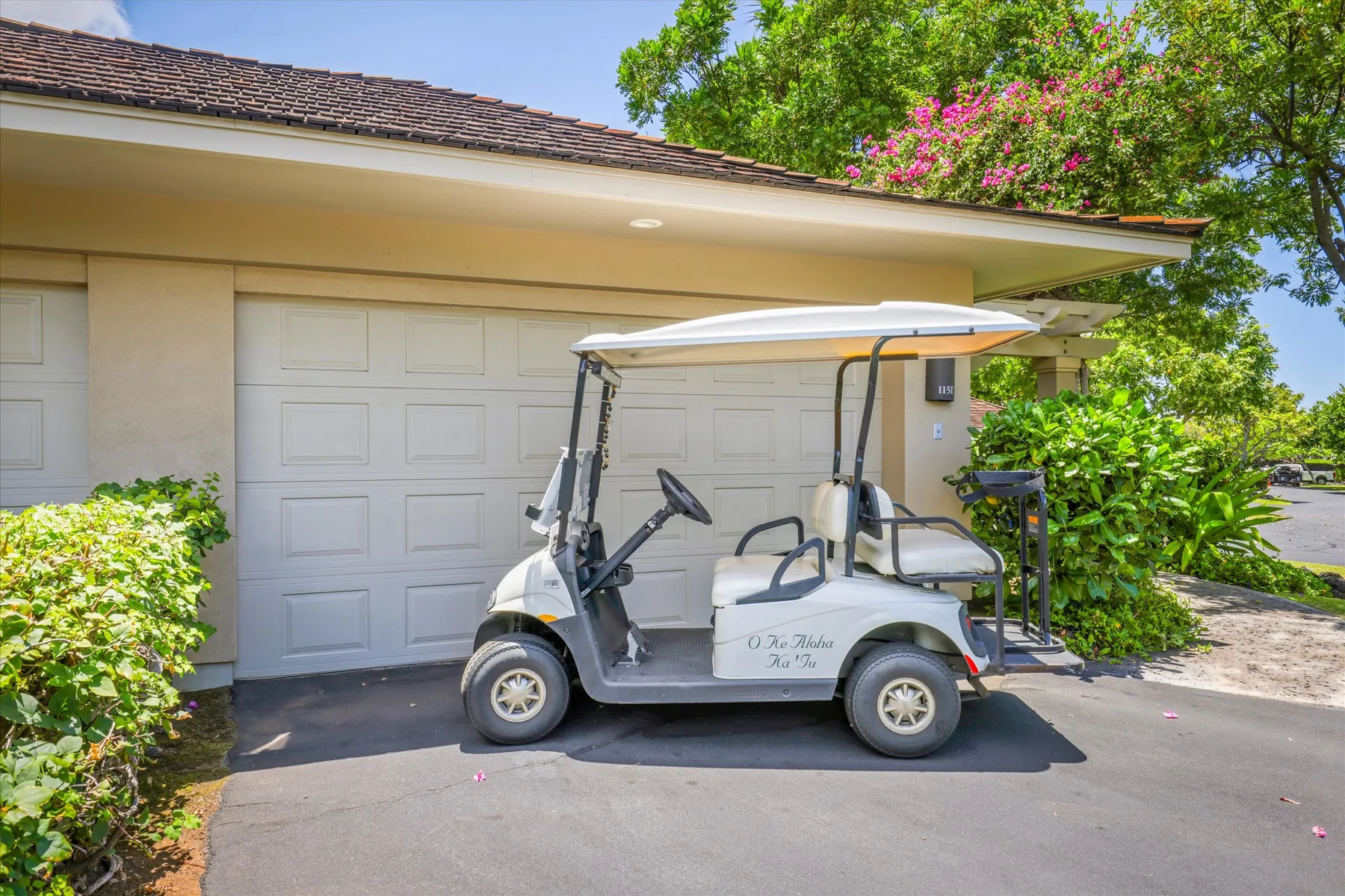 A golf cart is parked in front of a garage.