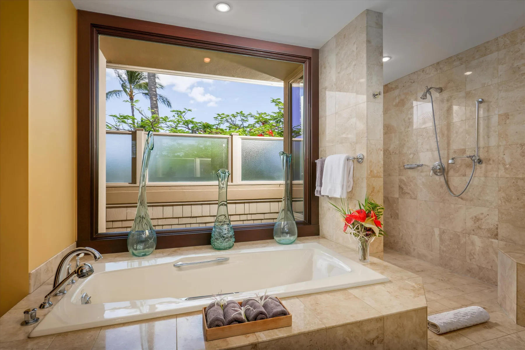 A bathroom with a bathtub beside a walk-in shower and a large window.