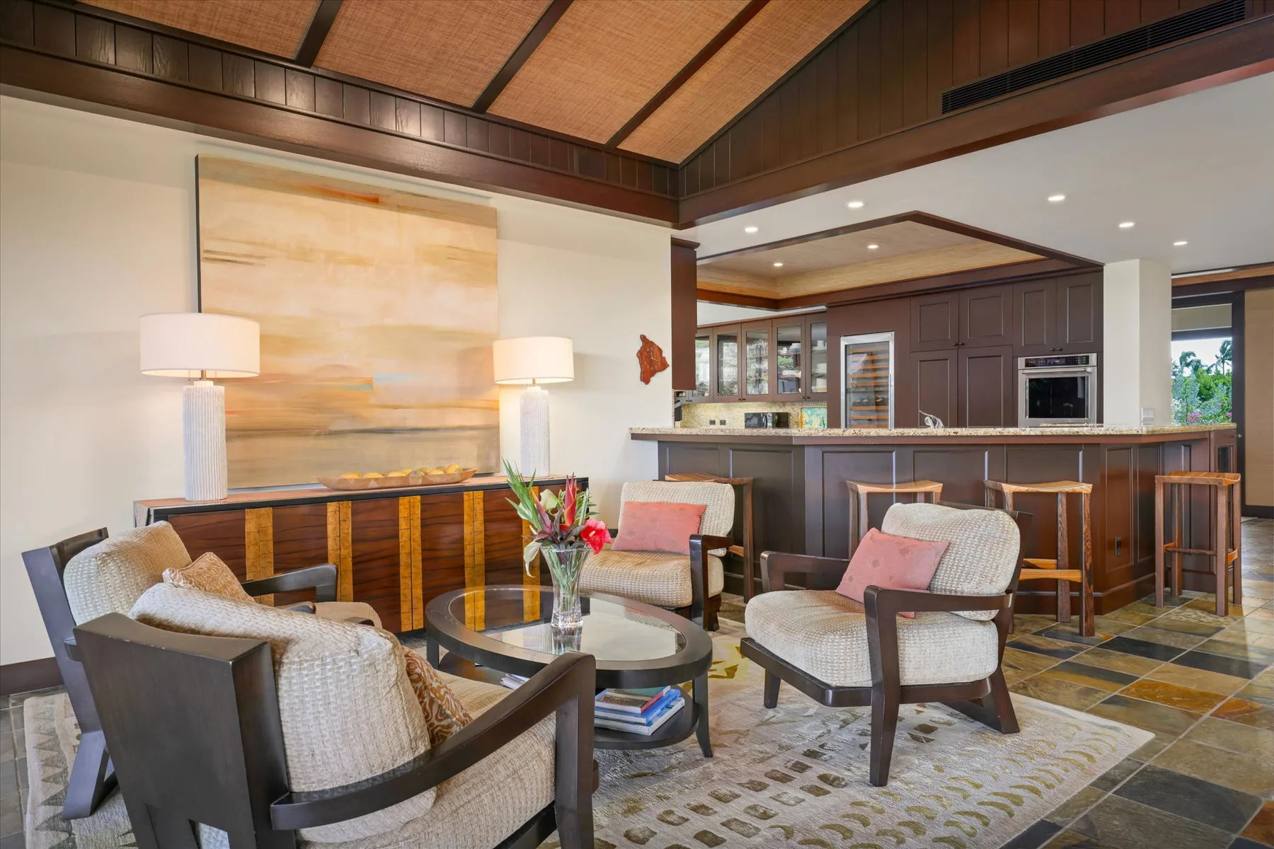 A lounge seating area faces a counter with stools and a kitchen behind it.