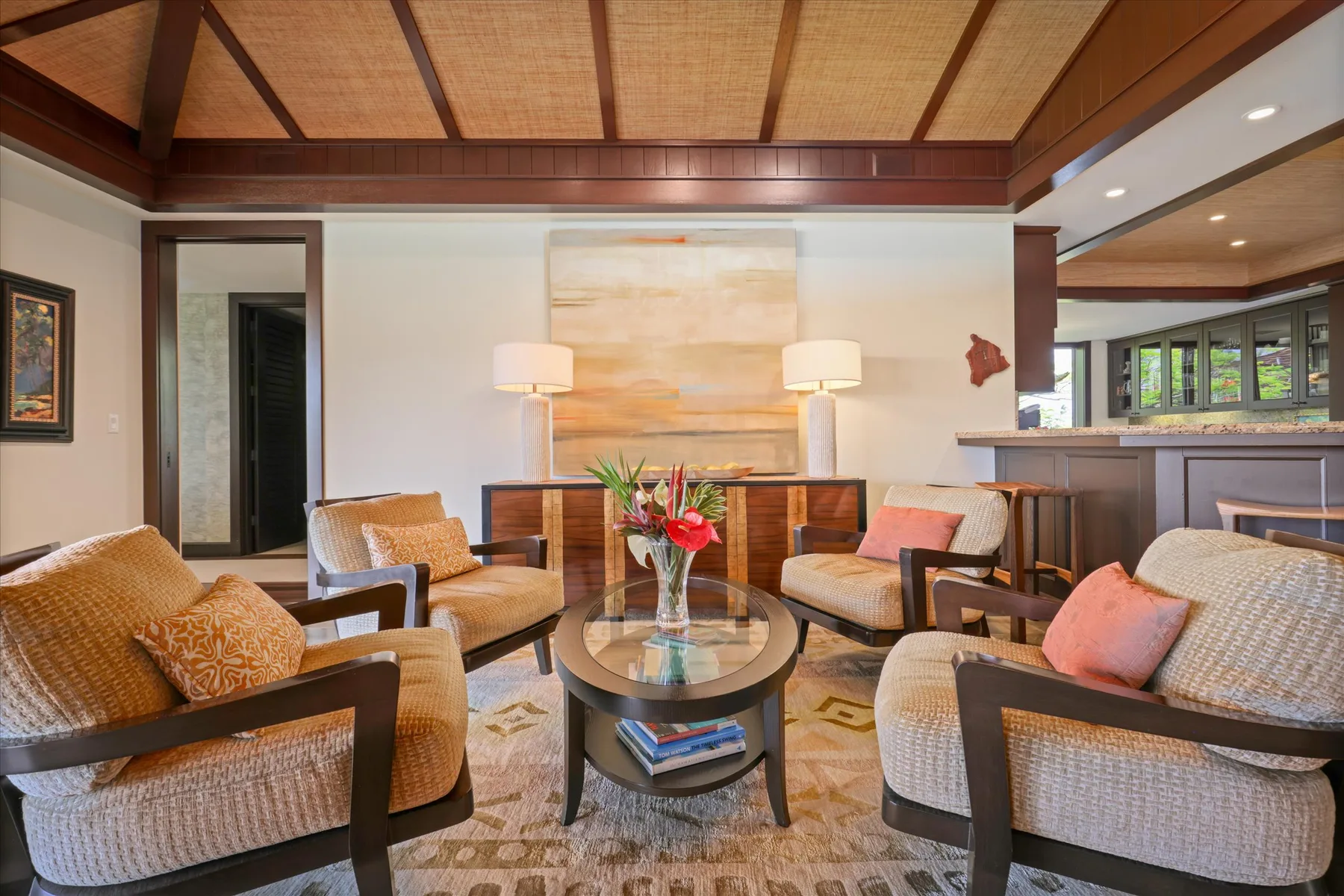 A furnished lounge with seating arranged around a coffee table beneath a timber ceiling.