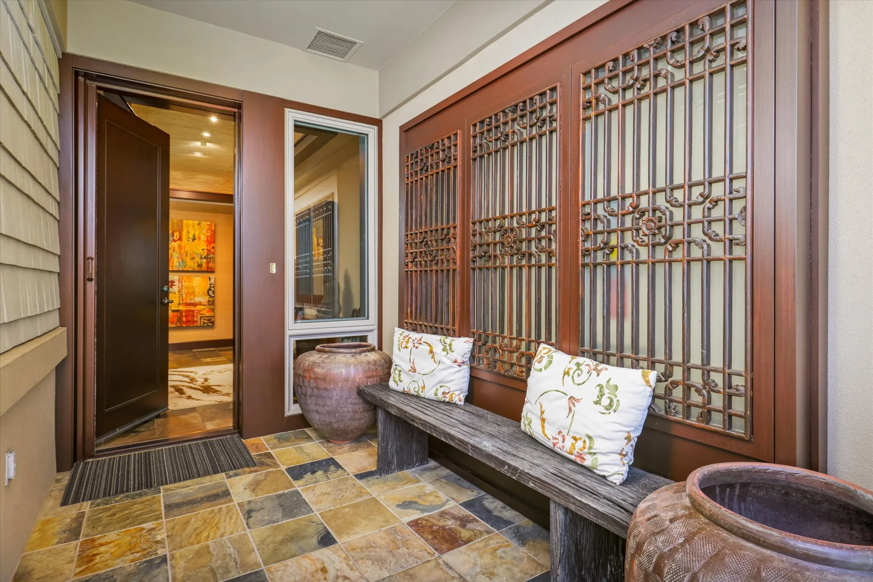 A tiled entryway with a wooden bench beneath decorative window grilles.