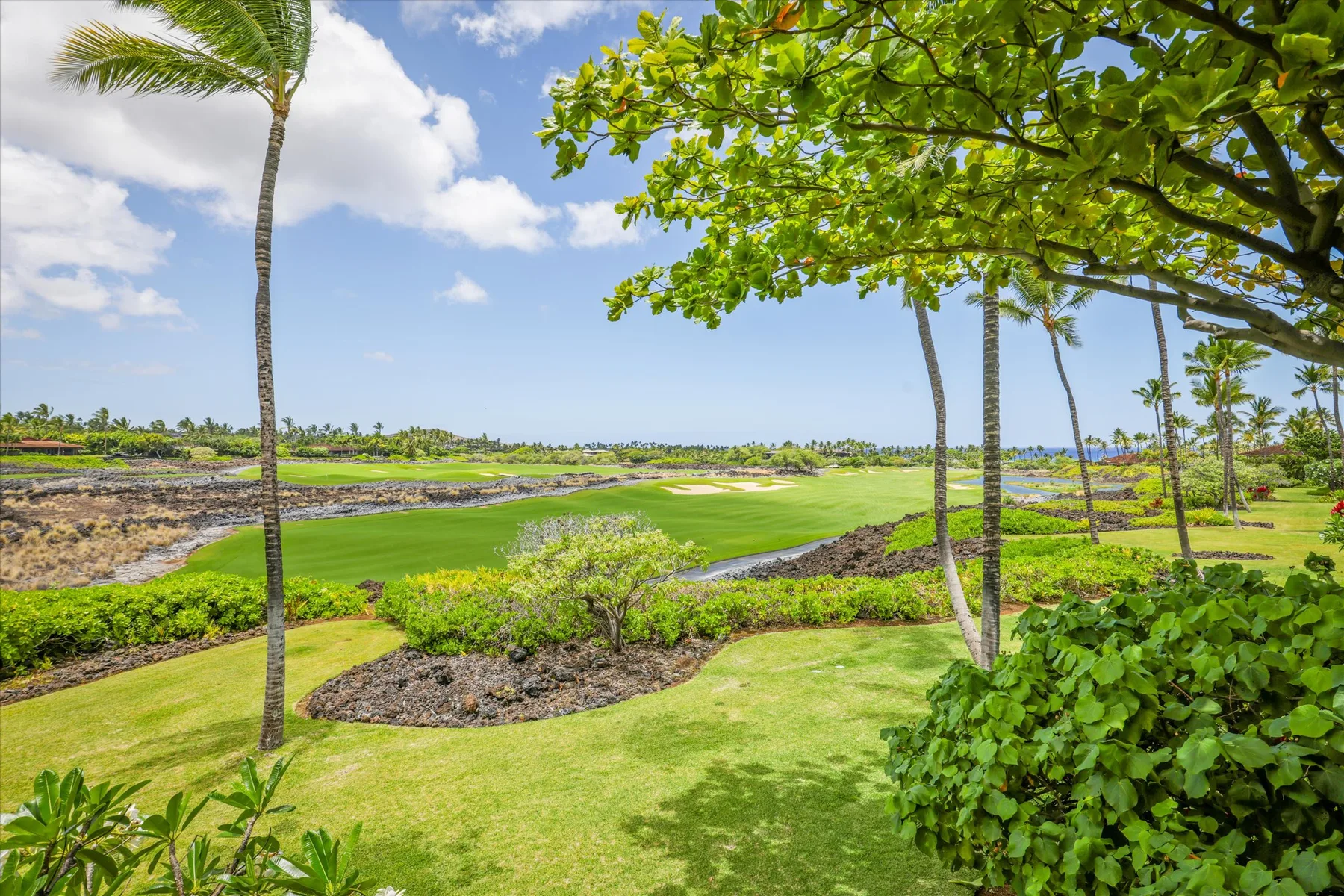 A landscaped golf course with green fairways, trees, and a pond.