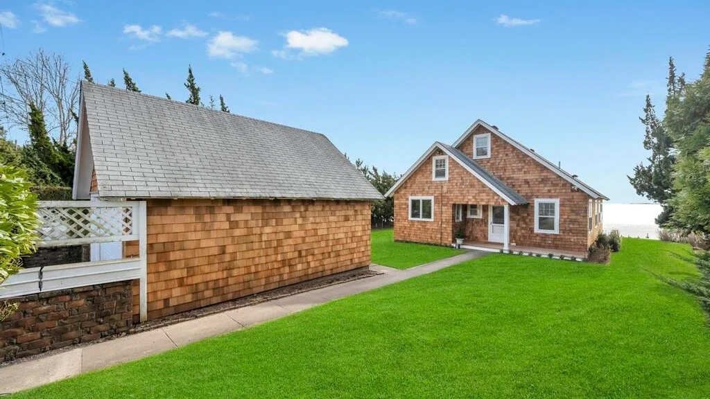 A brick house and outbuilding sit beside a broad green lawn.