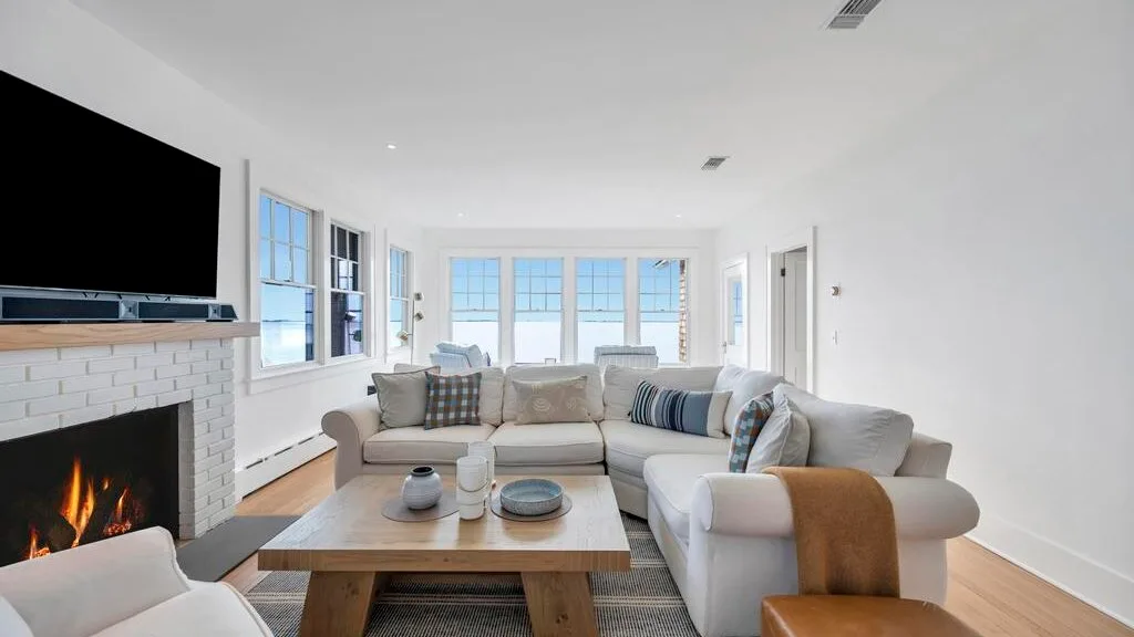 A bright living room with seating arranged around a low coffee table and fireplace.