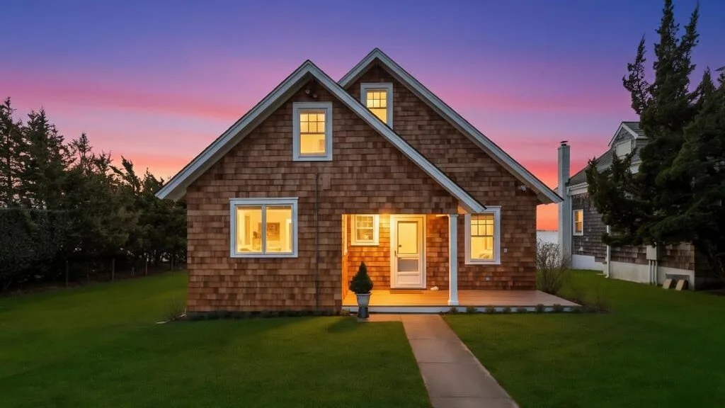 Una casa con ventanas iluminadas se alza junto a un sendero al atardecer.