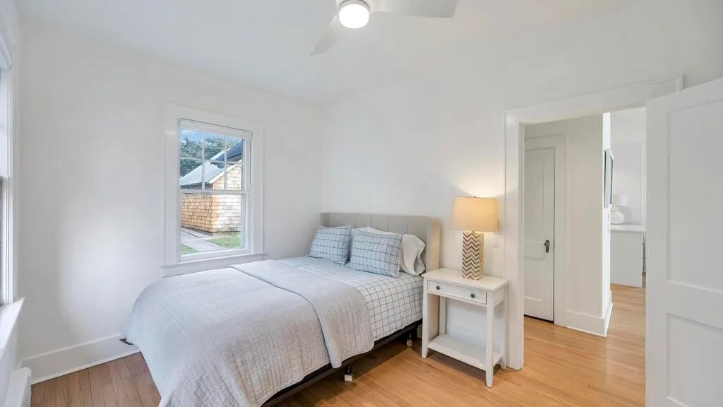 A bright bedroom with a neatly made bed and a bedside table.