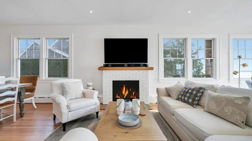 A bright living room with seating, a coffee table, and a fireplace.