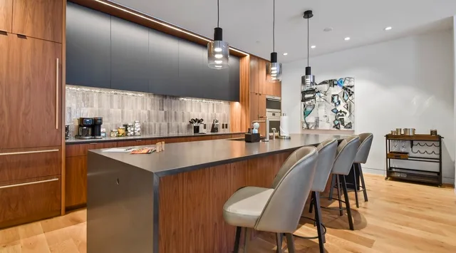 A modern kitchen with a long island and pendant lights.