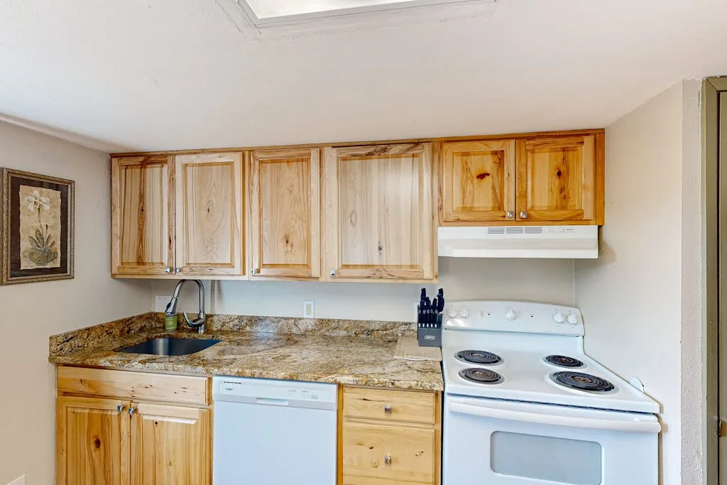 Una cocina con gabinetes de madera, una encimera, un fregadero y una estufa.