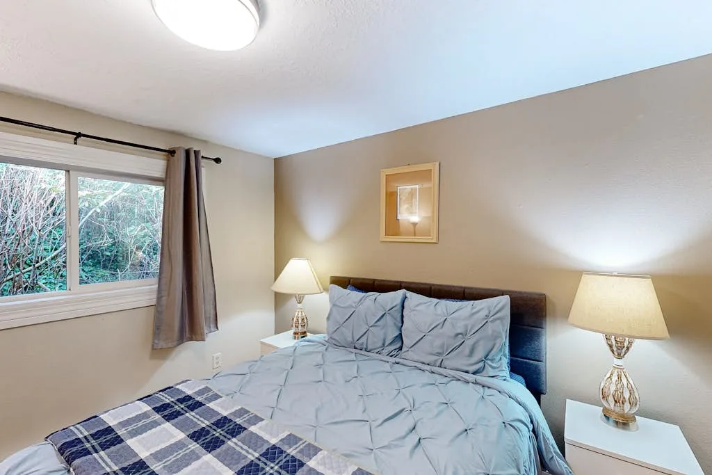 Un dormitorio con una cama, mesitas de noche y una ventana.