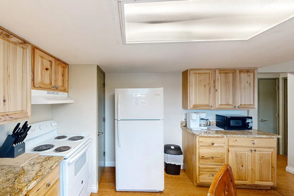 Una cocina con gabinetes de madera, un refrigerador y electrodomésticos para cocinar.