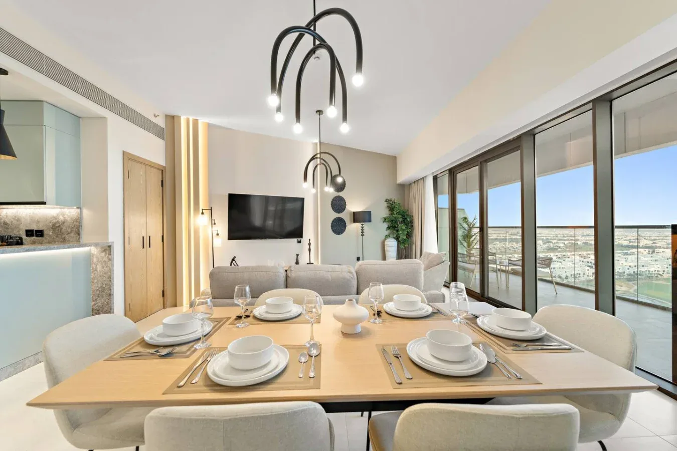 Comedor con la mesa puesta junto a ventanales de piso a techo.
