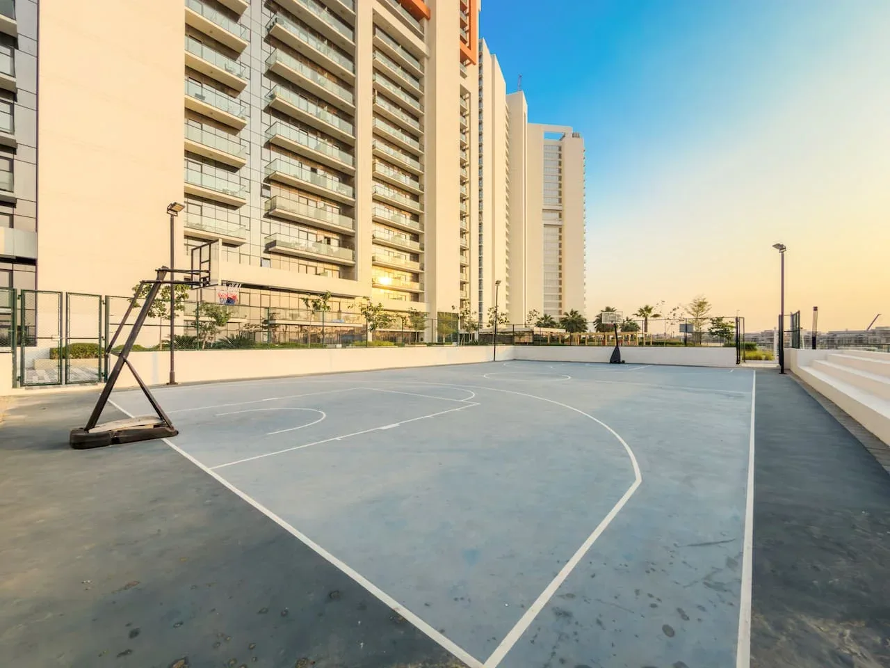Una cancha de baloncesto al aire libre está junto a varios edificios residenciales altos.