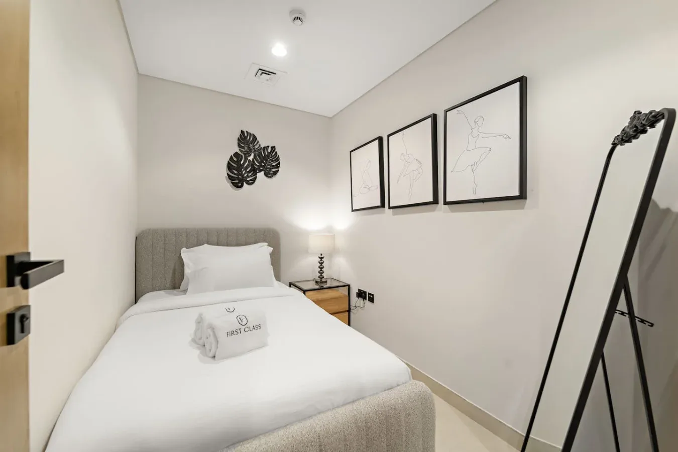 Un dormitorio luminoso con una cama bien hecha y obras enmarcadas en la pared.