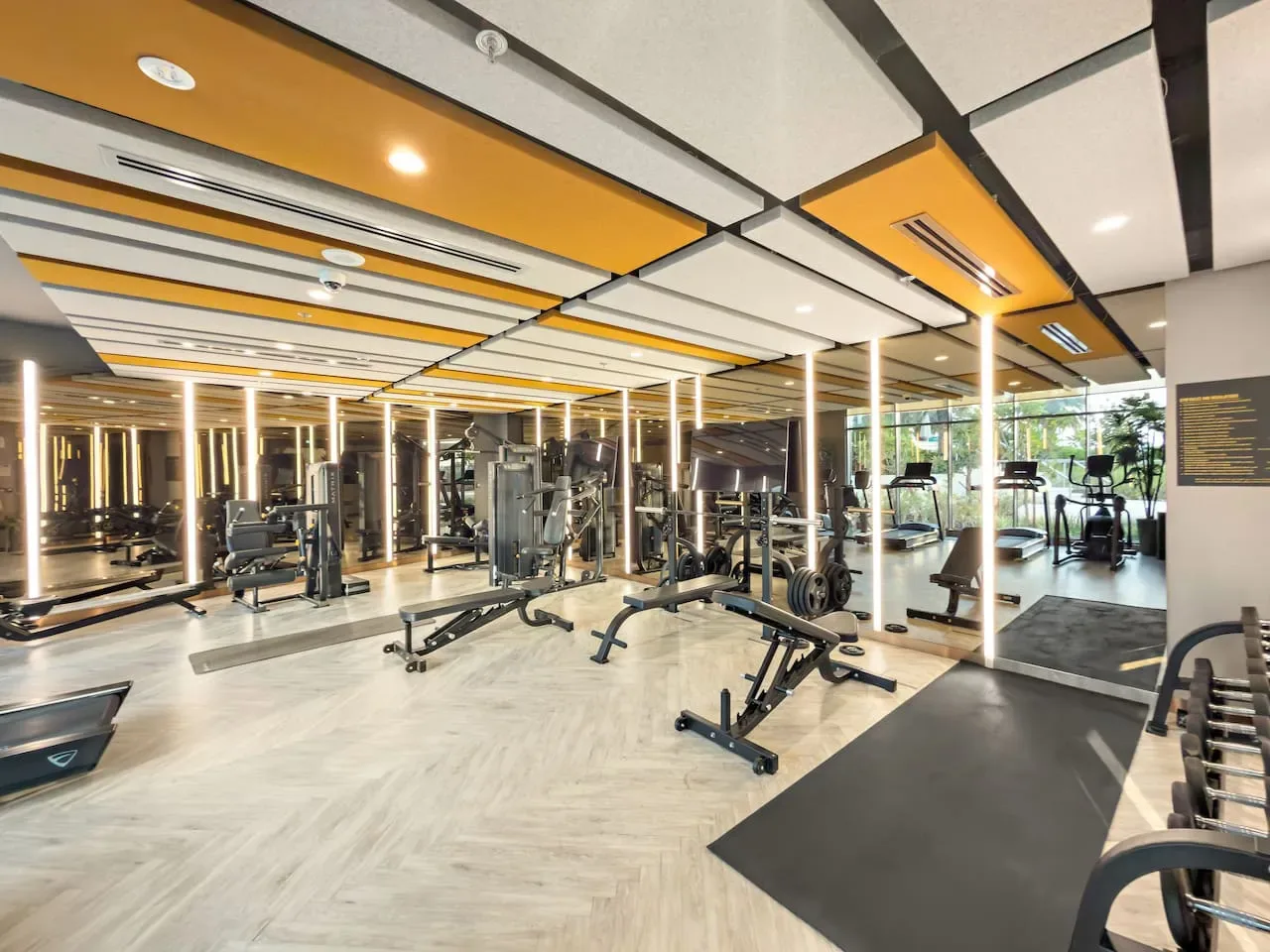 Un gimnasio con máquinas de ejercicio y paredes con espejos.
