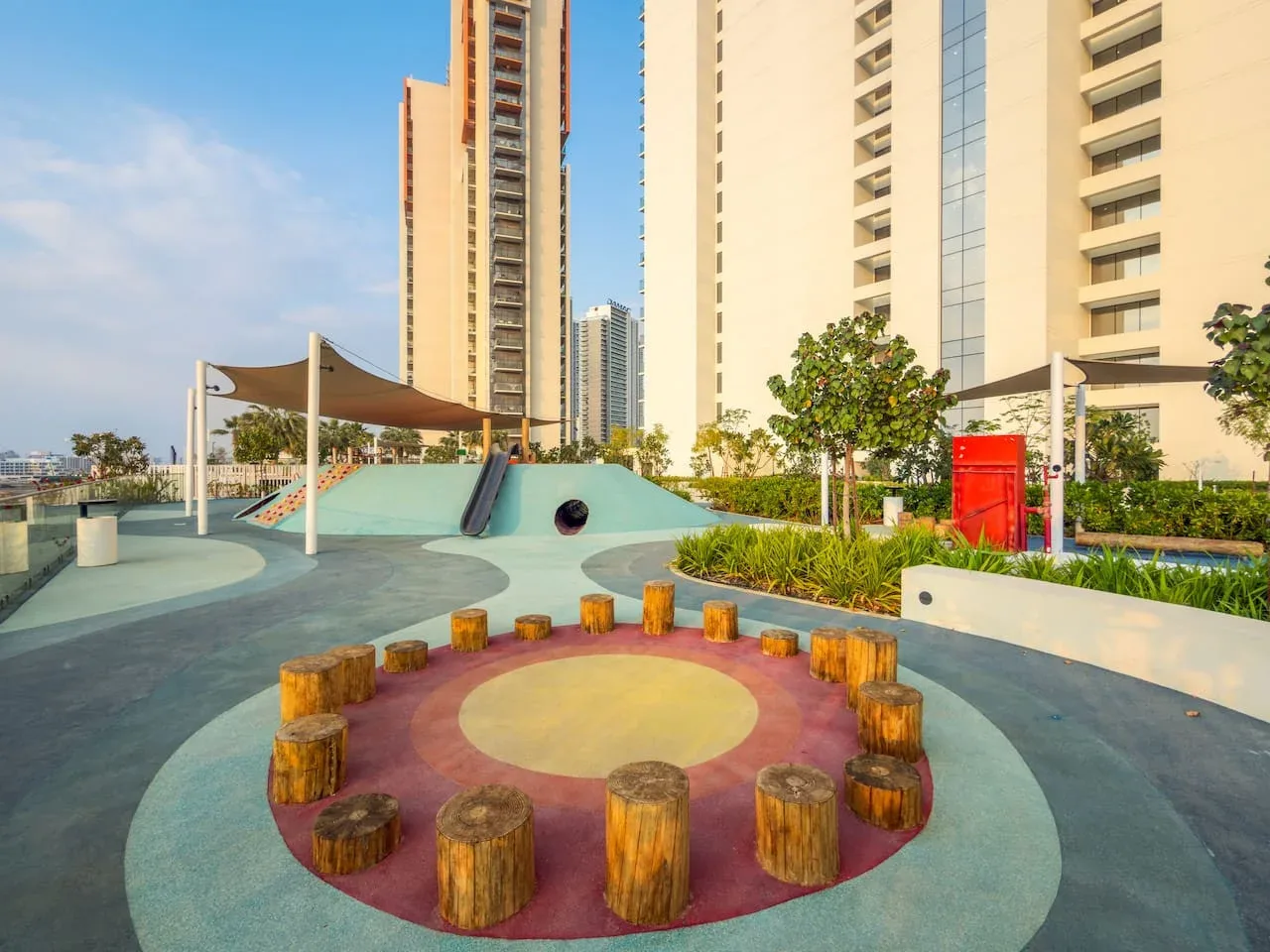 Una zona de juegos en la azotea tiene una superficie circular colorida y asientos bajos de madera.