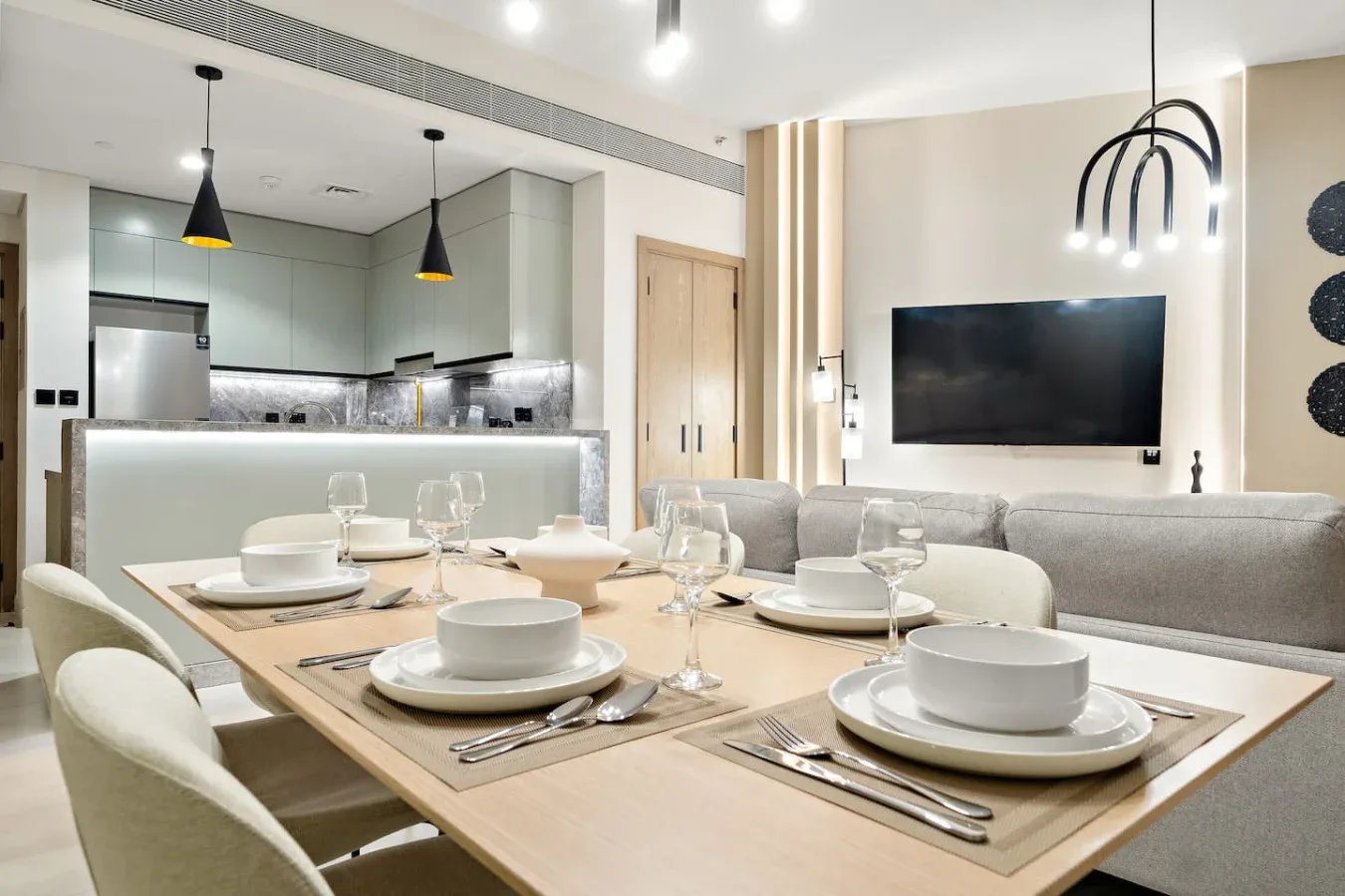 Comedor con la mesa puesta junto a una sala de estar y una cocina abierta.