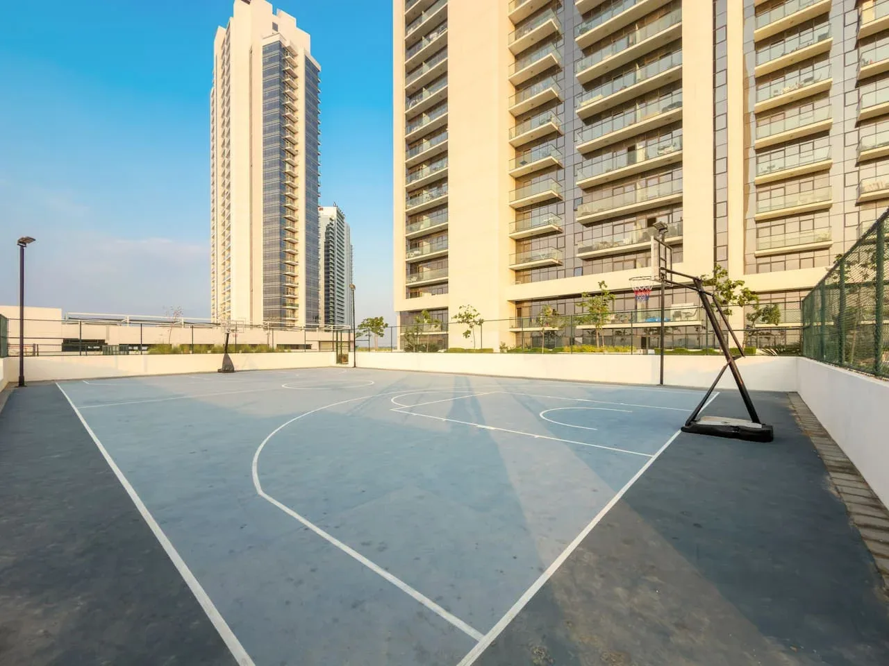 Una cancha de baloncesto al aire libre está junto a varios edificios altos.