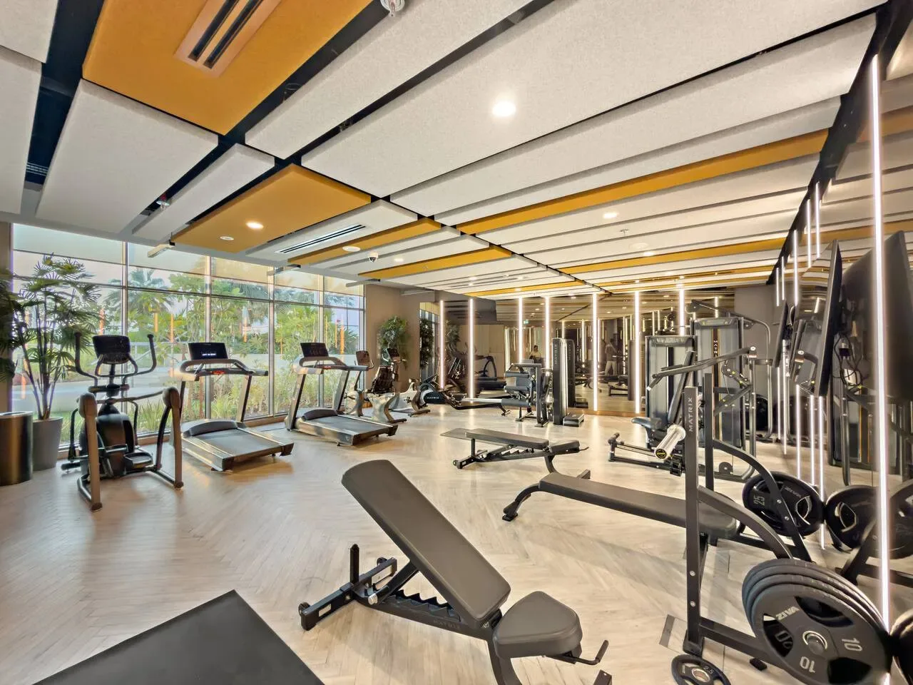 Un gimnasio amplio con máquinas de ejercicio y grandes ventanales.
