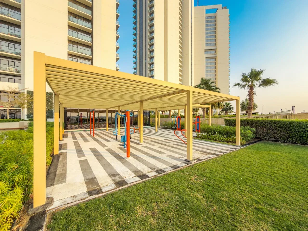 Un parque infantil al aire libre se encuentra bajo una cubierta junto a edificios residenciales altos.