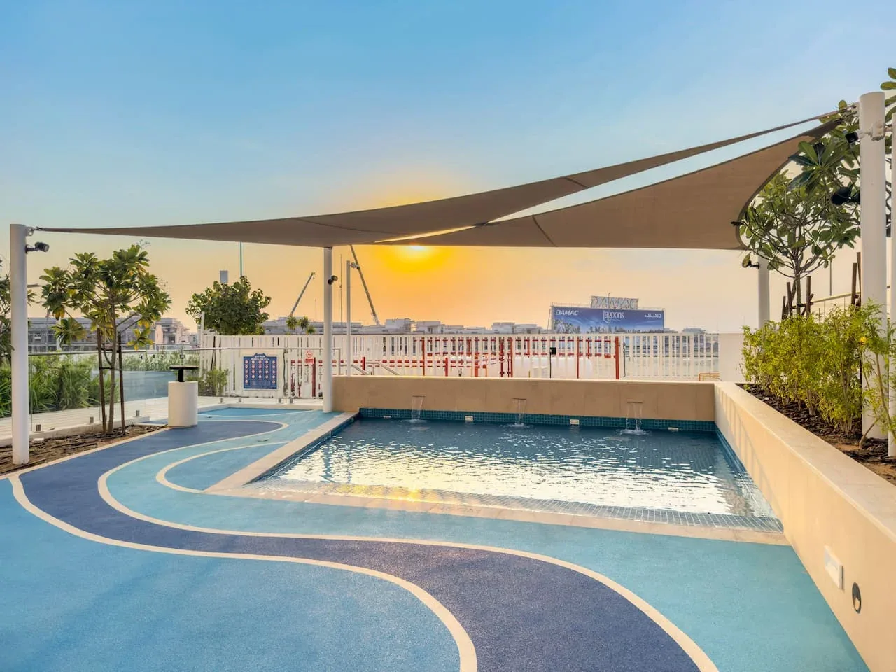 Una piscina en la azotea está bajo toldos, con el atardecer visible más allá de la barandilla.