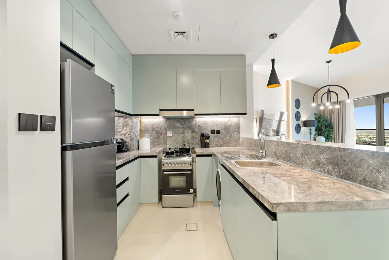 Una cocina moderna con gabinetes claros, electrodomésticos de acero inoxidable y una encimera de piedra.