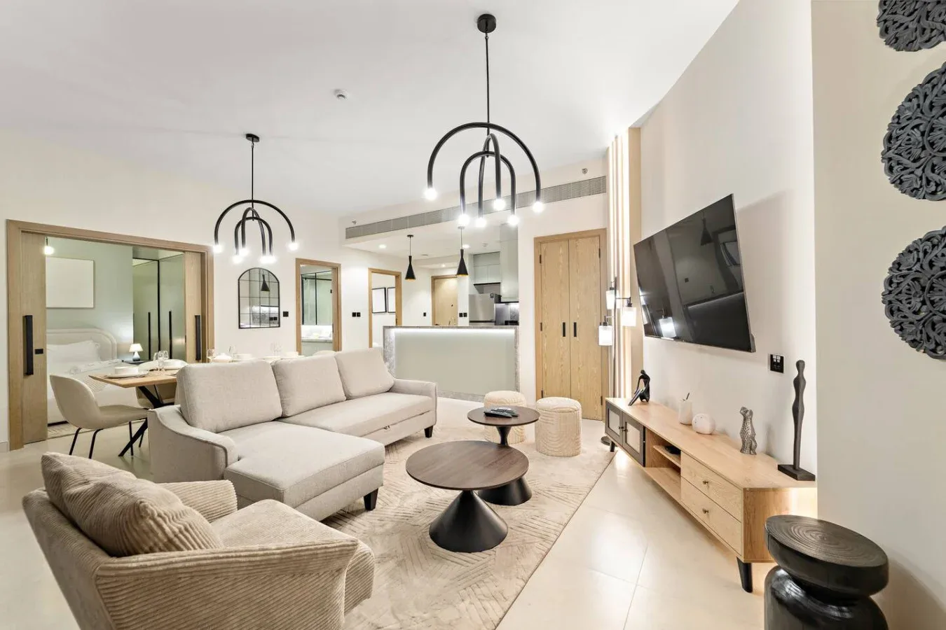 Salón de planta abierta con zona de estar, comedor y televisor en la pared.