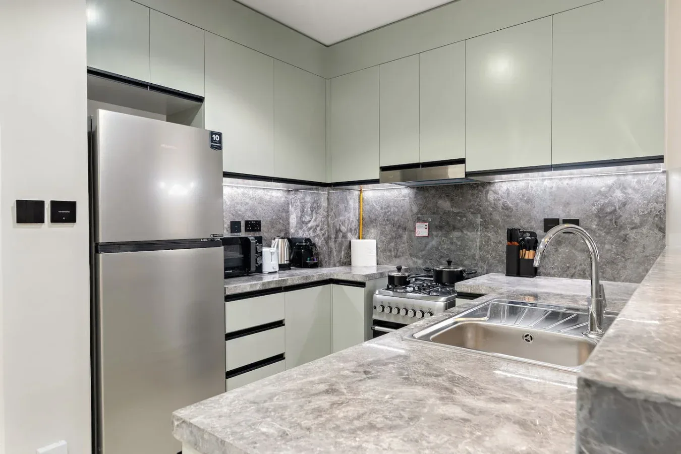 Una cocina moderna con gabinetes claros, refrigerador, estufa y fregadero.