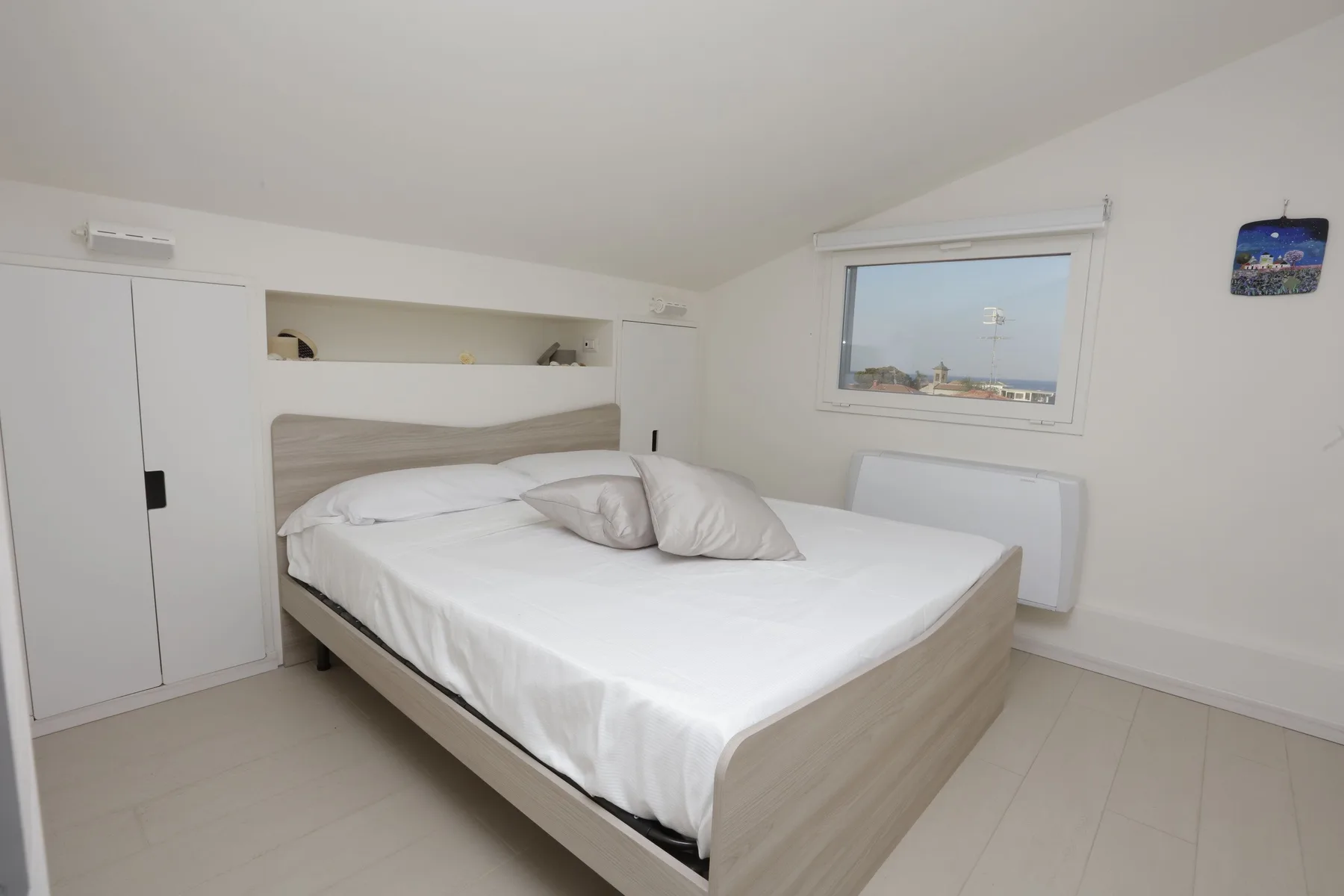 A bright bedroom with a neatly made bed and a window.